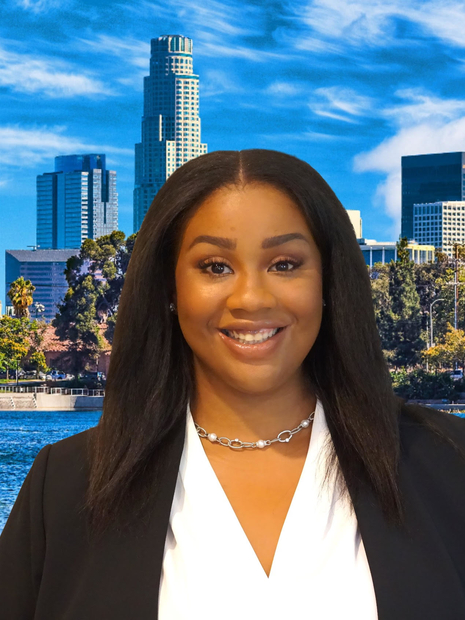 Brittany McKinley wearing a black blazer and white blouse with the city of LA view behind her