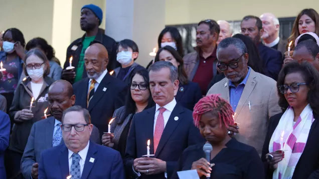City and Community leaders hold candles and bow their heads in prayer outside First AME Church.